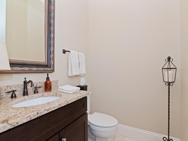 bathroom featuring toilet, vanity, and baseboards