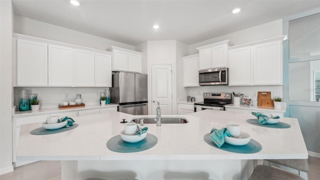 kitchen with white cabinetry, appliances with stainless steel finishes, light tile patterned floors, and a breakfast bar