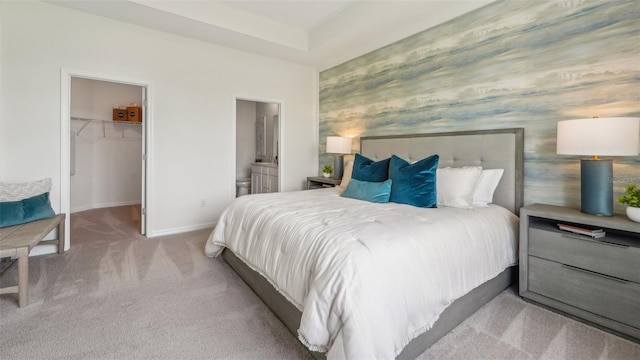 carpeted bedroom featuring ensuite bath, a closet, and a walk in closet