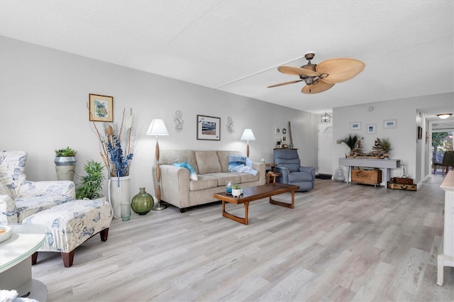 living room with a textured ceiling, light hardwood / wood-style flooring, and ceiling fan