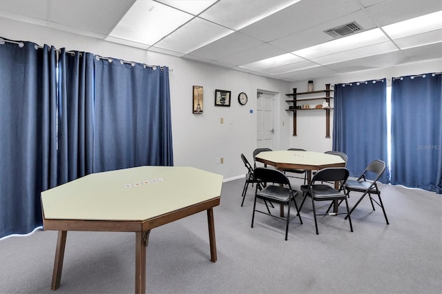 carpeted dining space with a drop ceiling