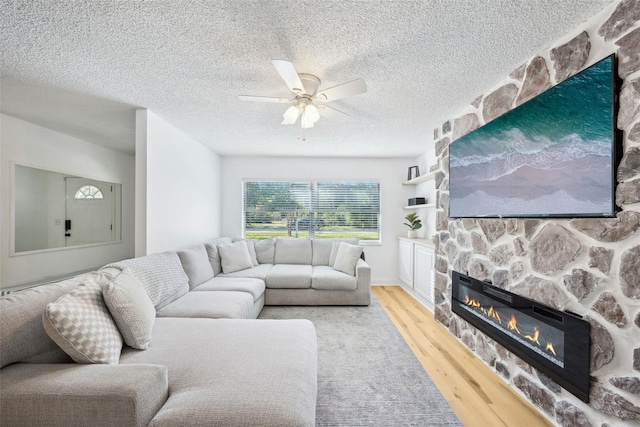 living room with a textured ceiling, a fireplace, hardwood / wood-style flooring, and ceiling fan