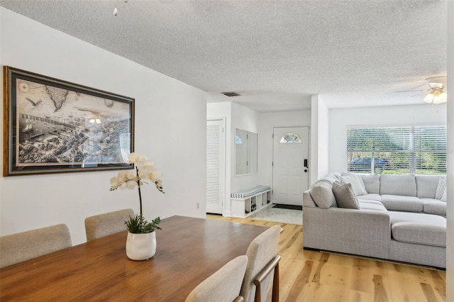 dining area with ceiling fan, a textured ceiling, and light hardwood / wood-style flooring