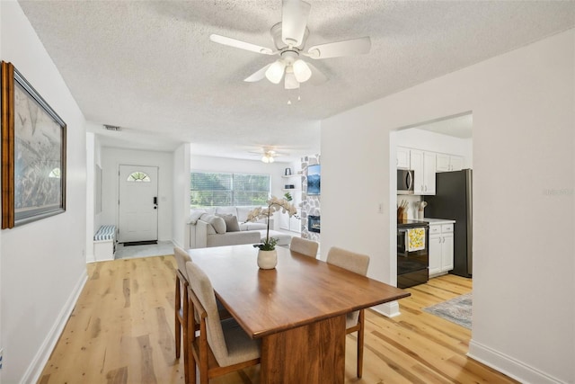 dining area with ceiling fan, a textured ceiling, and light hardwood / wood-style floors