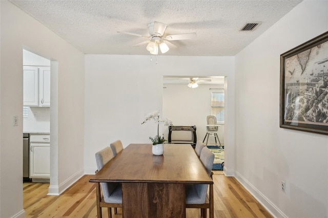 dining room with light hardwood / wood-style flooring, a textured ceiling, and ceiling fan