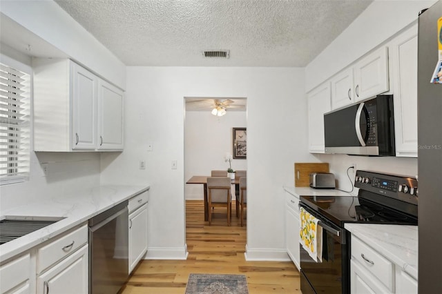 kitchen with stainless steel appliances, light stone countertops, white cabinets, and light hardwood / wood-style flooring