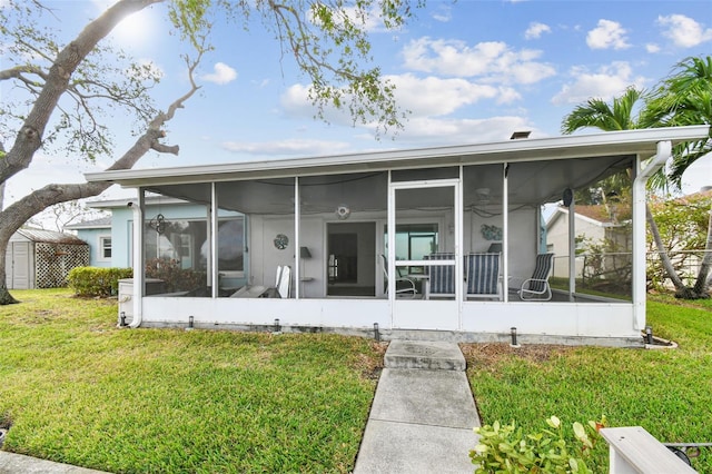 back of house featuring a lawn and a sunroom