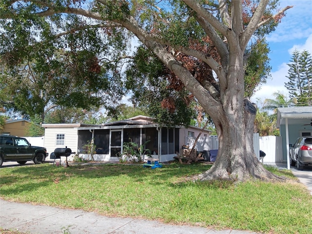 view of front of property with a sunroom, a carport, and a front yard