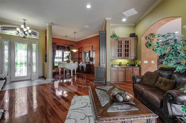 living room with dark hardwood / wood-style floors, ornamental molding, a chandelier, and decorative columns