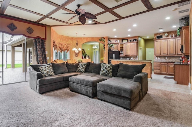 carpeted living room with beamed ceiling, coffered ceiling, and ceiling fan with notable chandelier