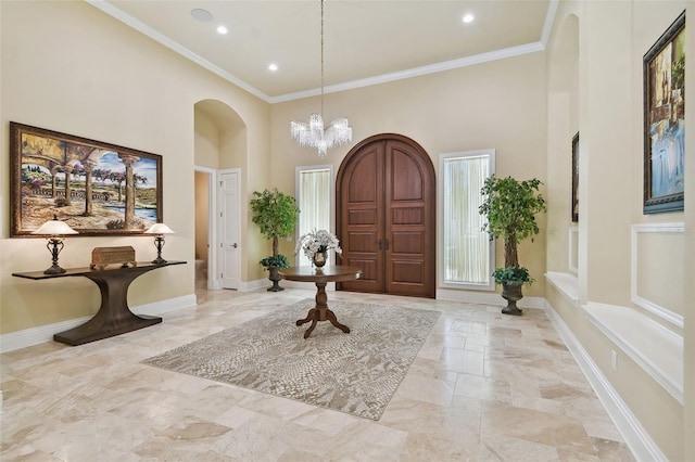 entrance foyer featuring a towering ceiling, a chandelier, and ornamental molding