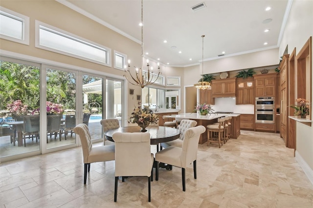 dining room with ornamental molding, a high ceiling, and a chandelier