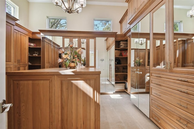 walk in closet with a towering ceiling, light carpet, and a chandelier