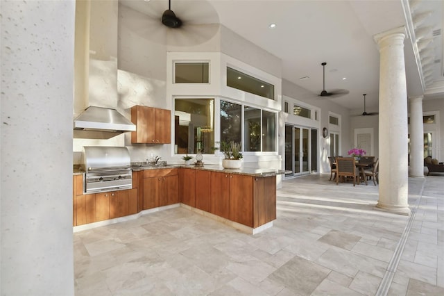 kitchen with ceiling fan, kitchen peninsula, a towering ceiling, and decorative columns