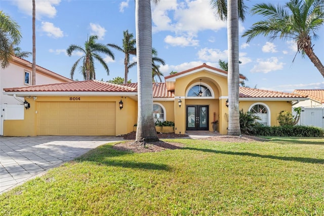 mediterranean / spanish home featuring a front yard, french doors, a garage, and stucco siding