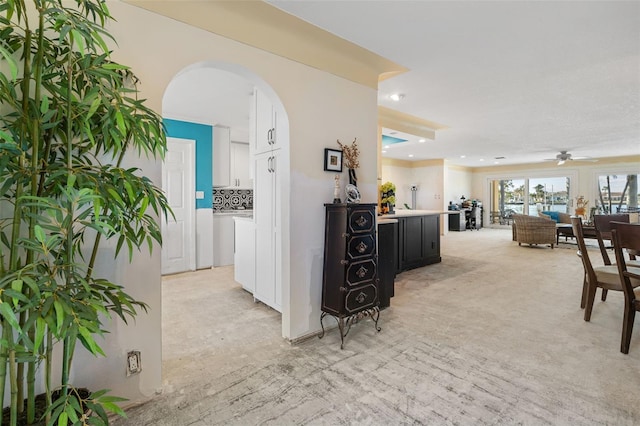 hallway featuring arched walkways, recessed lighting, and light colored carpet