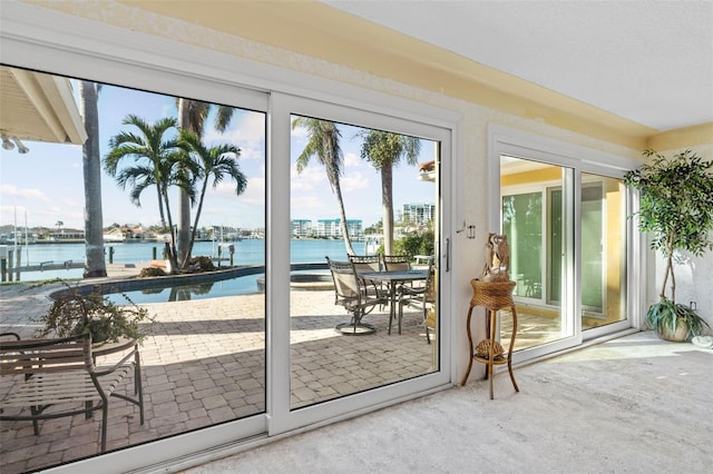 doorway to outside with a water view and carpet floors