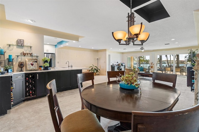 dining area with ceiling fan with notable chandelier and sink