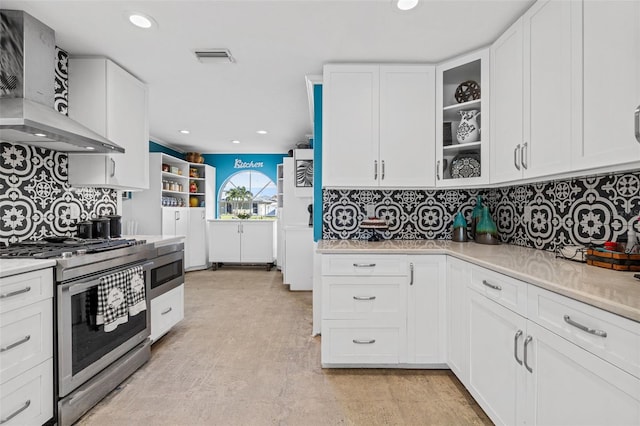 kitchen featuring white cabinetry, light countertops, wall chimney range hood, and stainless steel range with electric cooktop