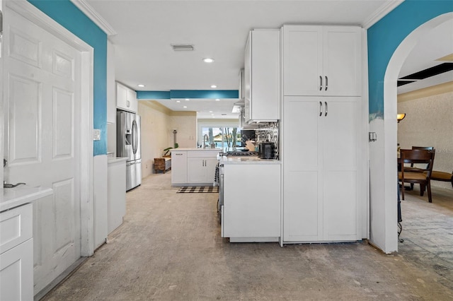 kitchen featuring a peninsula, white cabinets, recessed lighting, and stainless steel fridge