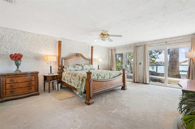 bedroom with ceiling fan, access to exterior, a textured ceiling, and a water view