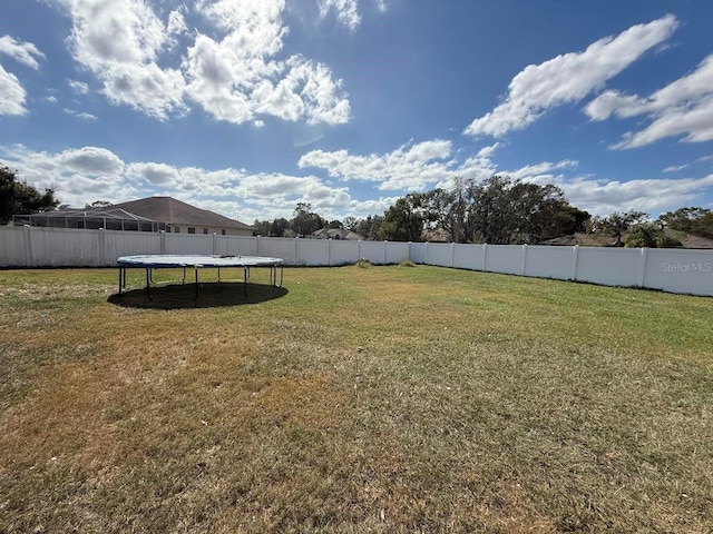 view of yard with a trampoline and a fenced backyard