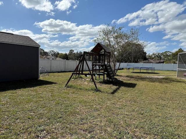 view of jungle gym featuring a fenced backyard, a yard, an outbuilding, and a trampoline