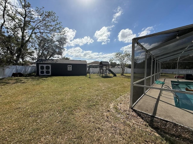 view of yard with glass enclosure, a fenced in pool, a fenced backyard, an outdoor structure, and a playground