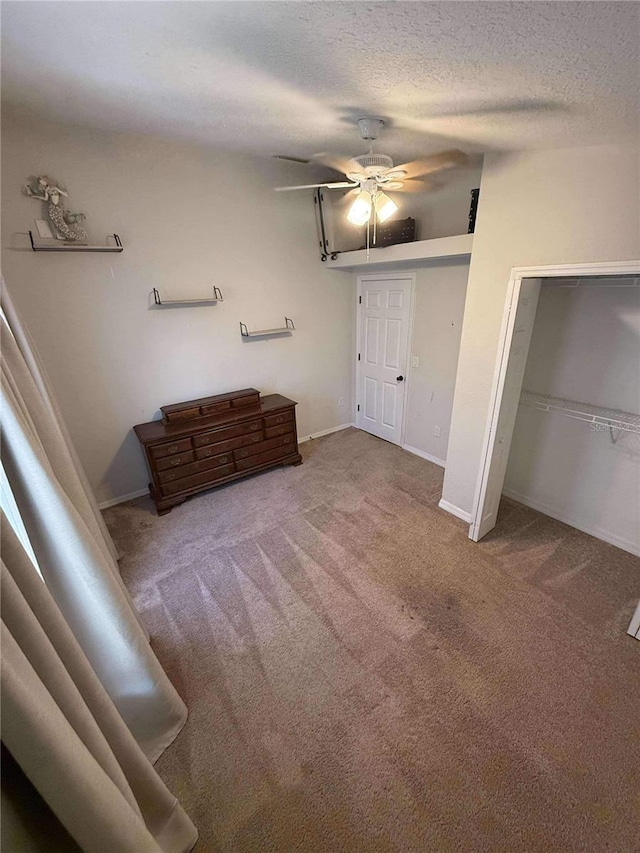 unfurnished bedroom featuring baseboards, carpet floors, a textured ceiling, and ceiling fan