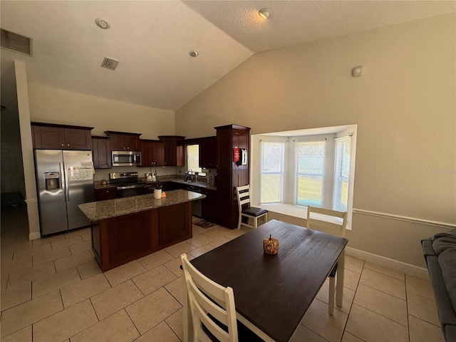 kitchen featuring visible vents, a kitchen island, light tile patterned floors, stainless steel appliances, and a sink