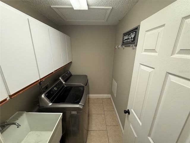 laundry room featuring light tile patterned floors, attic access, cabinet space, a sink, and washer and dryer