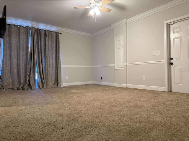 carpeted spare room with crown molding, baseboards, and ceiling fan