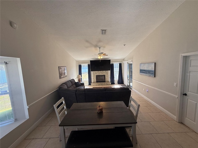 dining area with visible vents, lofted ceiling, a fireplace, a textured ceiling, and a ceiling fan