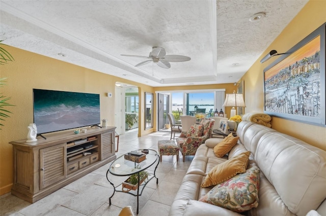 tiled living room featuring a raised ceiling, ceiling fan, and a textured ceiling