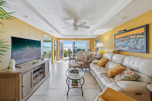 living room with a textured ceiling, a tray ceiling, and ceiling fan