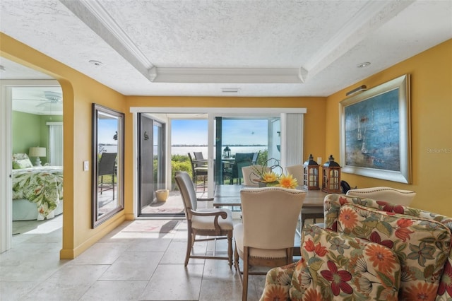 tiled dining area featuring a textured ceiling and a tray ceiling