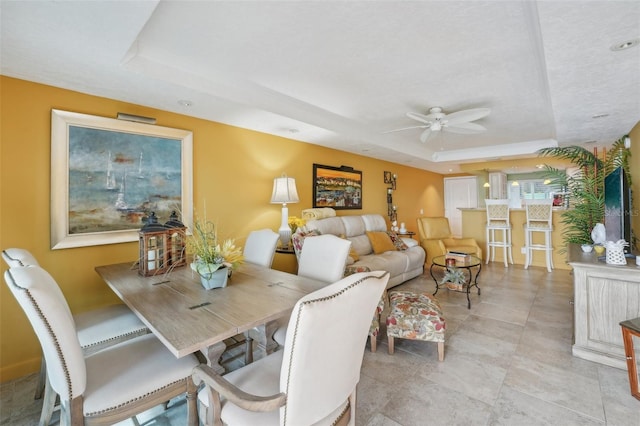 dining room featuring a raised ceiling and ceiling fan