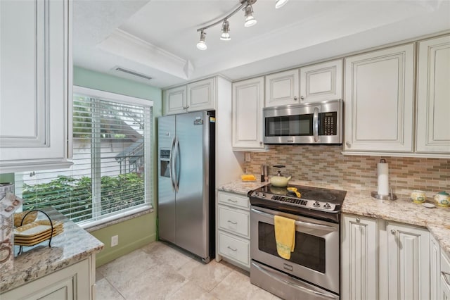 kitchen featuring backsplash, a raised ceiling, light stone countertops, white cabinetry, and stainless steel appliances