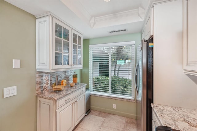 kitchen with backsplash, white cabinets, stainless steel fridge, light stone countertops, and light tile patterned floors