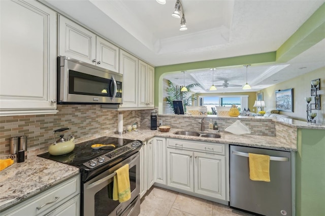 kitchen featuring appliances with stainless steel finishes, backsplash, a tray ceiling, sink, and white cabinets