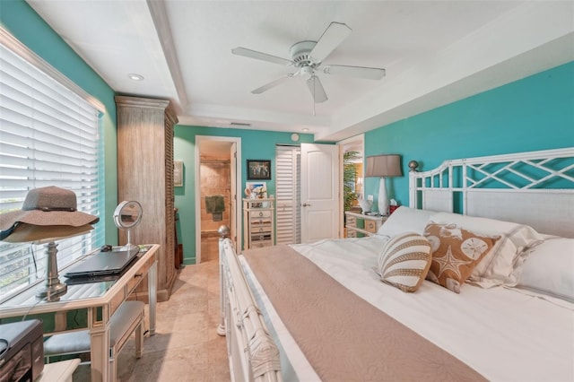 bedroom featuring a tray ceiling, ceiling fan, a closet, and light tile patterned floors