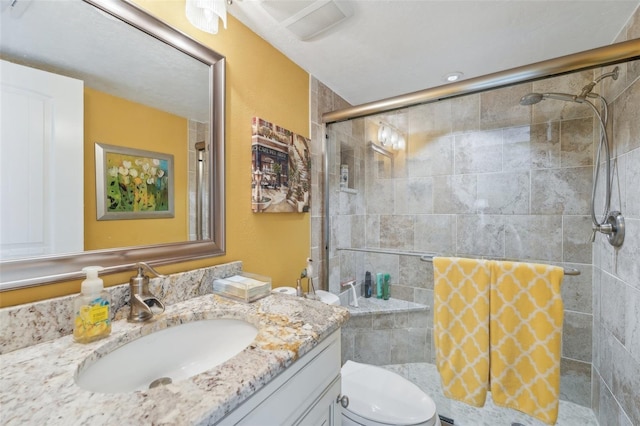 bathroom featuring vanity, a shower with shower door, and toilet