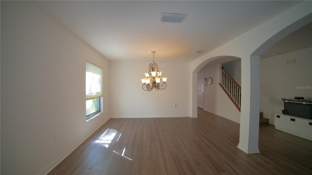 unfurnished room featuring dark wood-type flooring and an inviting chandelier