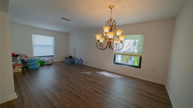 interior space featuring dark wood-type flooring, an inviting chandelier, and a healthy amount of sunlight