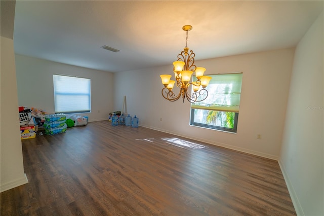 unfurnished dining area featuring dark wood-type flooring and a chandelier