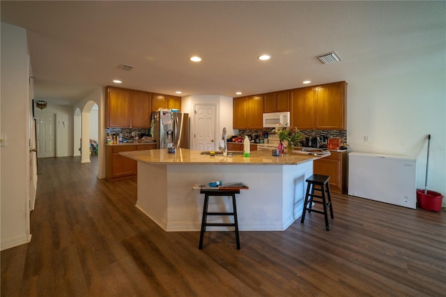 kitchen featuring stainless steel fridge, dark hardwood / wood-style floors, and decorative backsplash