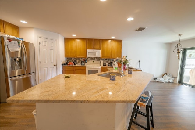 kitchen featuring sink, tasteful backsplash, a kitchen breakfast bar, white appliances, and dark wood-type flooring