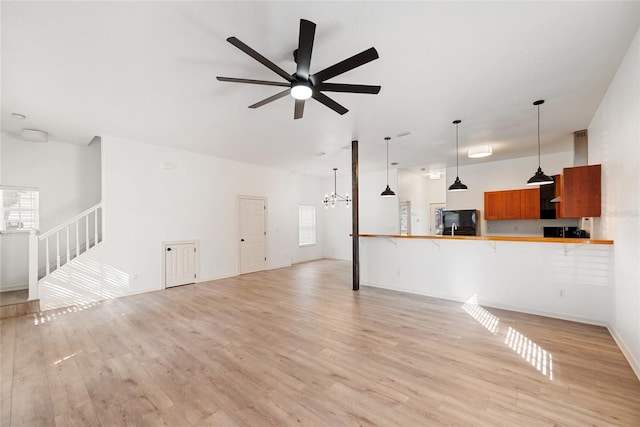 living room with ceiling fan with notable chandelier and light hardwood / wood-style flooring