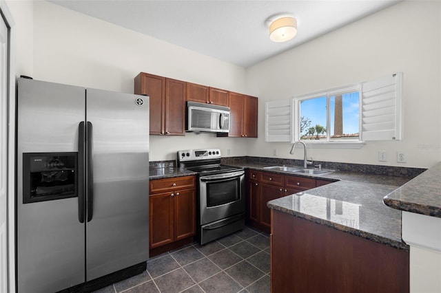 403 S Oregon Ave, Tampa, FL 33606 - kitchen with a peninsula, a sink, dark stone counters, dark tile patterned flooring, and appliances with stainless steel finishes