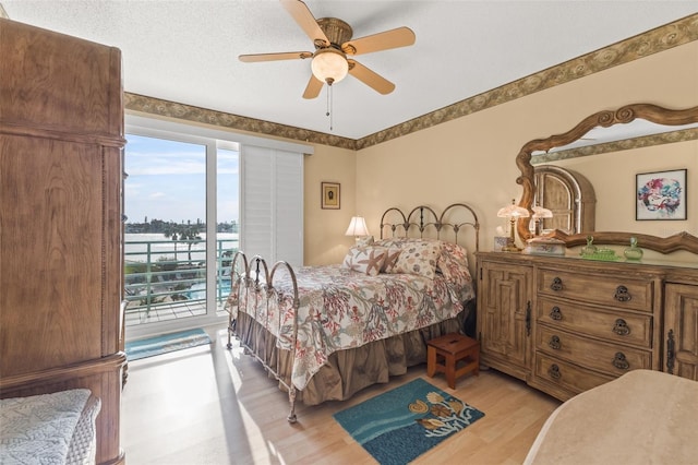 bedroom featuring access to outside, light wood-type flooring, a textured ceiling, and ceiling fan